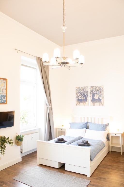 een witte slaapkamer met een wit bed en een kroonluchter bij Apartment Wiesbaden Mitte, Zentral am Park, Congresscenter 5 min, Bahnhof 10min in Wiesbaden