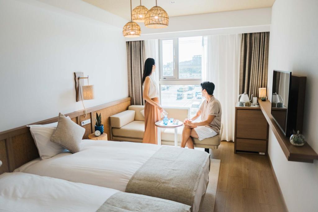 a man and woman sitting in a hotel room at Hotel Resol Trinity Naha in Naha