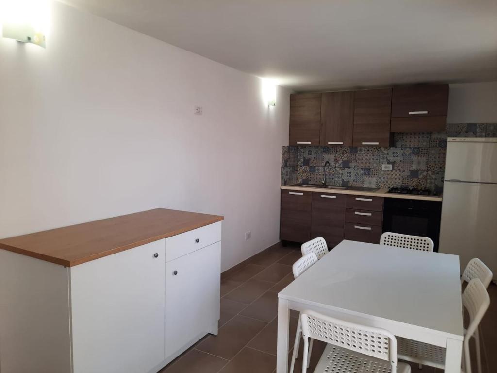 a kitchen with a table and a white table and chairs at Perla Bianca in Marina di Lizzano