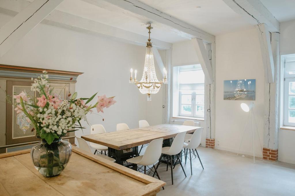 a dining room with a table and a vase of flowers at NordseeEstate - Loft unter Reet mit Sauna in Tetenbüll