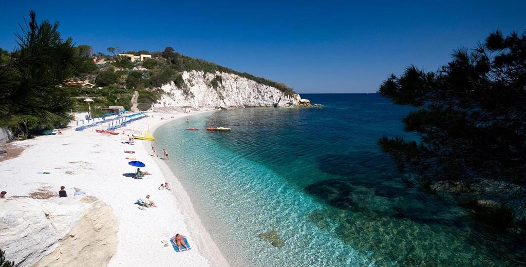 una playa con gente tirada en la arena y el agua en Residence Capobianco, en Portoferraio