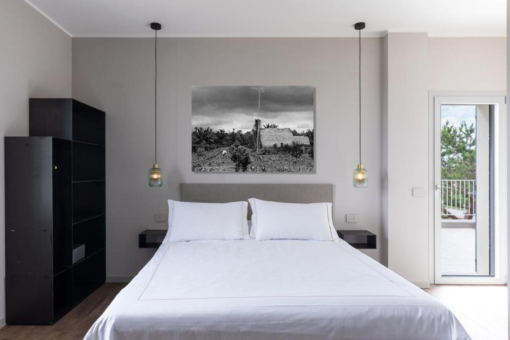 Un dormitorio con una gran cama blanca y una ventana en El Patio, en San Vito Rimini