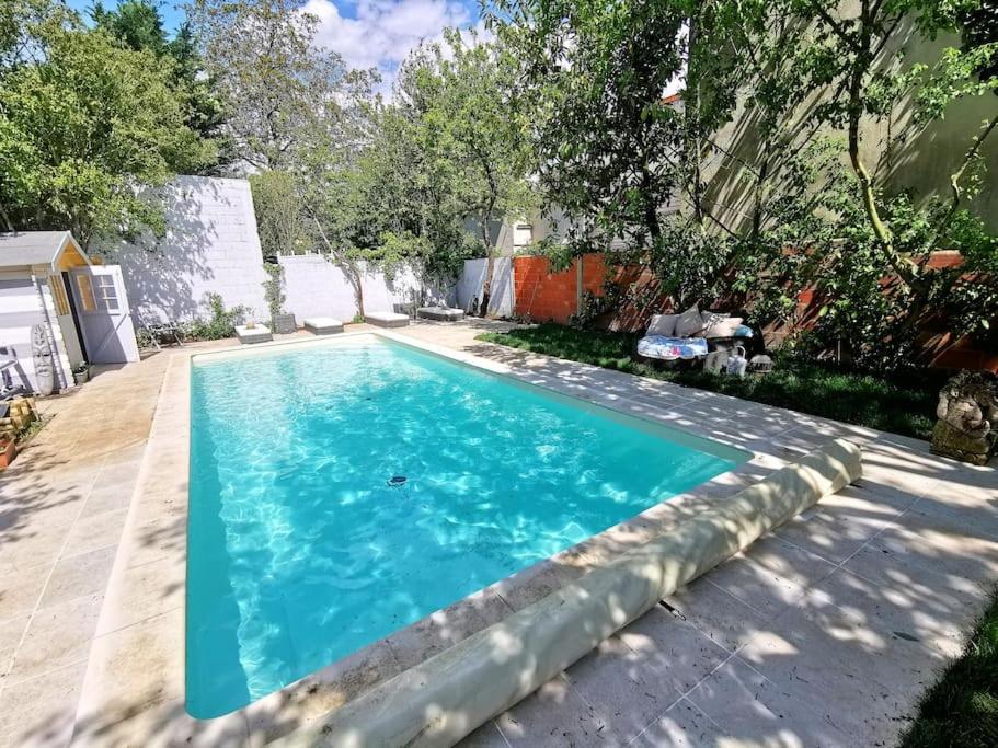 une piscine avec de l'eau bleue dans une cour dans l'établissement La maison du bonheur, à Montreuil