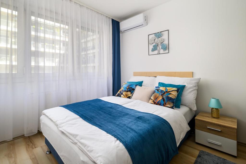 um quarto com uma cama grande com lençóis azuis e brancos em Studio with FREE GARAGE & AC em Budapeste