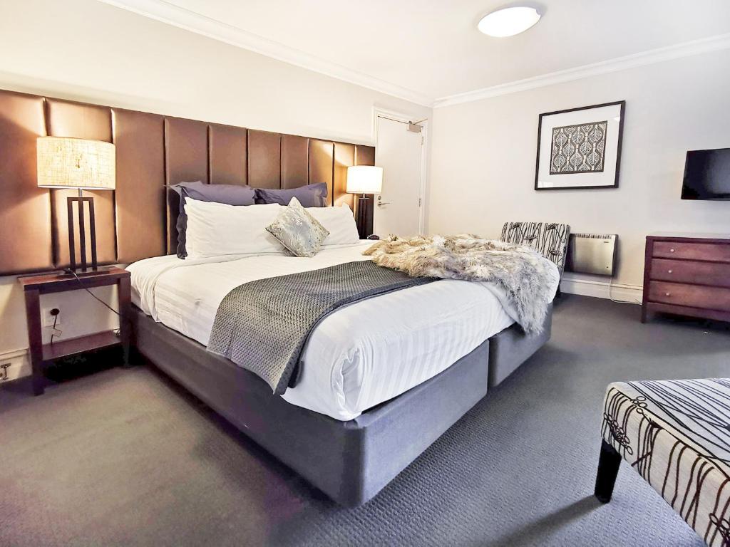 a bedroom with a large bed with a wooden headboard at The Beacon - Luxe Studio Unit in Queenstown
