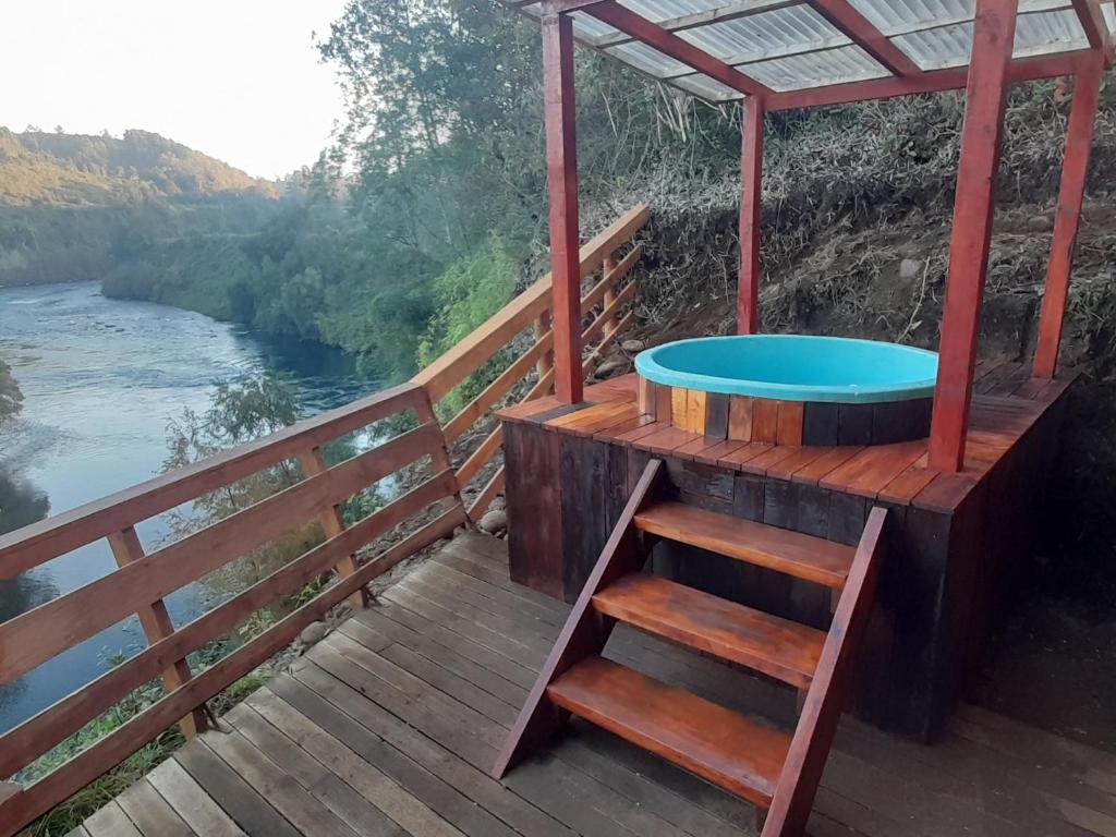 a hot tub on a wooden deck next to a river at cabaña trafwe in Lago Ranco