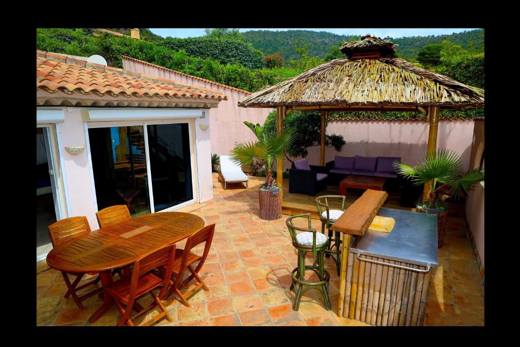 a patio with a wooden table and a gazebo at Dans Baptiste traditionnellle appartement de la plage et terrasse Balli in Rayol-Canadel-sur-Mer