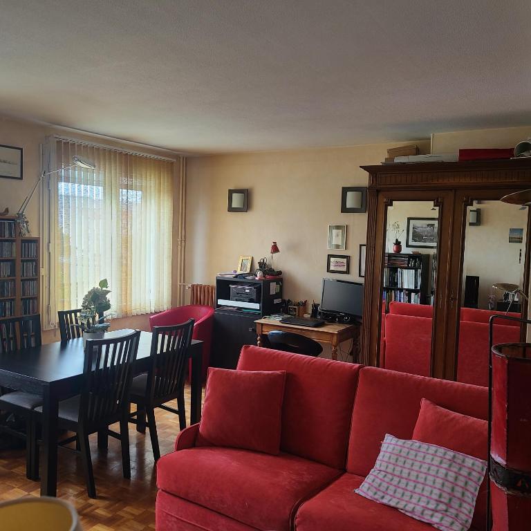 un salon avec un canapé rouge et une table dans l'établissement Grand 2 pièces - Proche Métro & Stade de France, à Saint-Denis