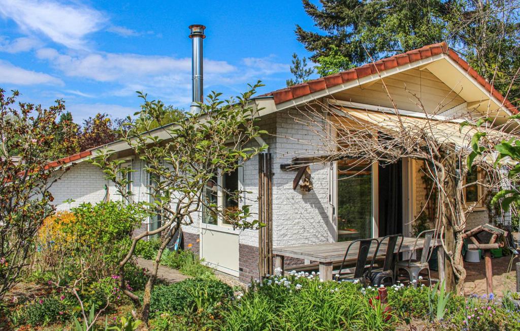 ein weißes Cottage mit einem Picknicktisch im Garten in der Unterkunft Vlak aan het bos genieten van de rust & natuur. in Putten