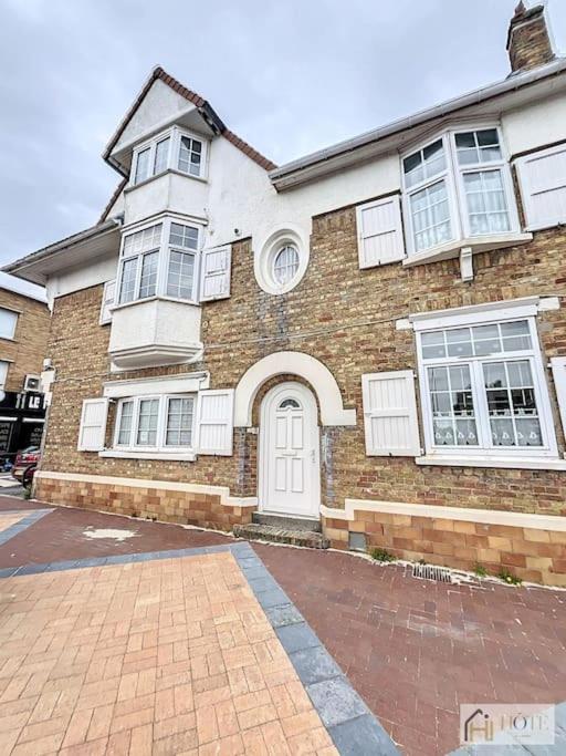 une maison en briques avec une porte et des fenêtres blanches dans l'établissement Appartement place Rubben - 2 pas de la Mer, à Bray-Dunes