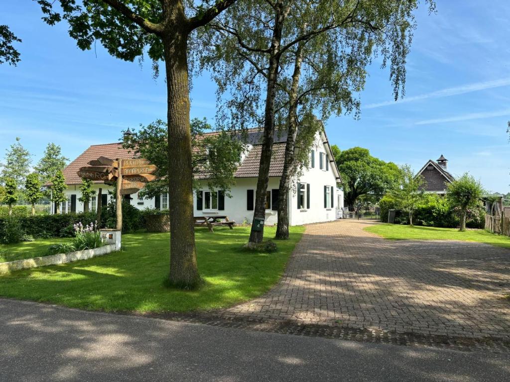 uma casa branca com árvores e uma entrada em De Hazeldonck em Gemert