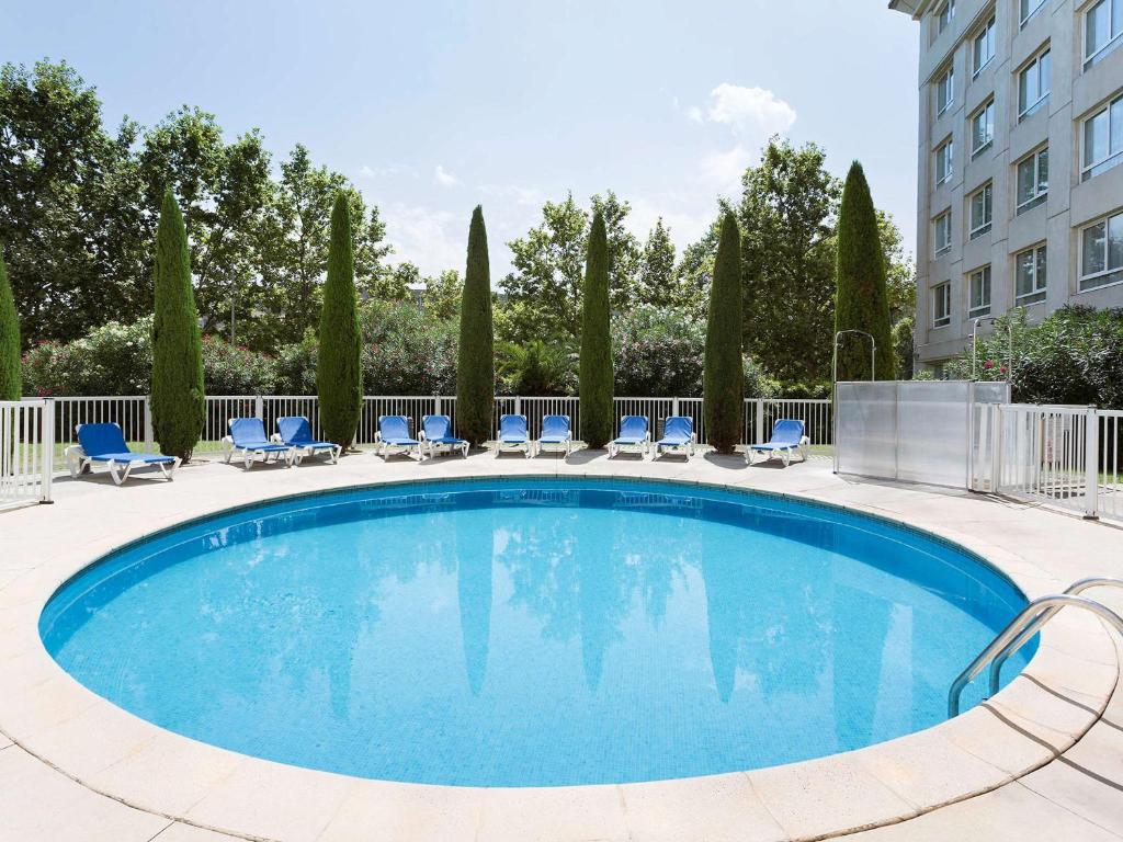 une piscine avec des chaises et un bâtiment dans l'établissement Novotel Suites Montpellier Antigone, à Montpellier