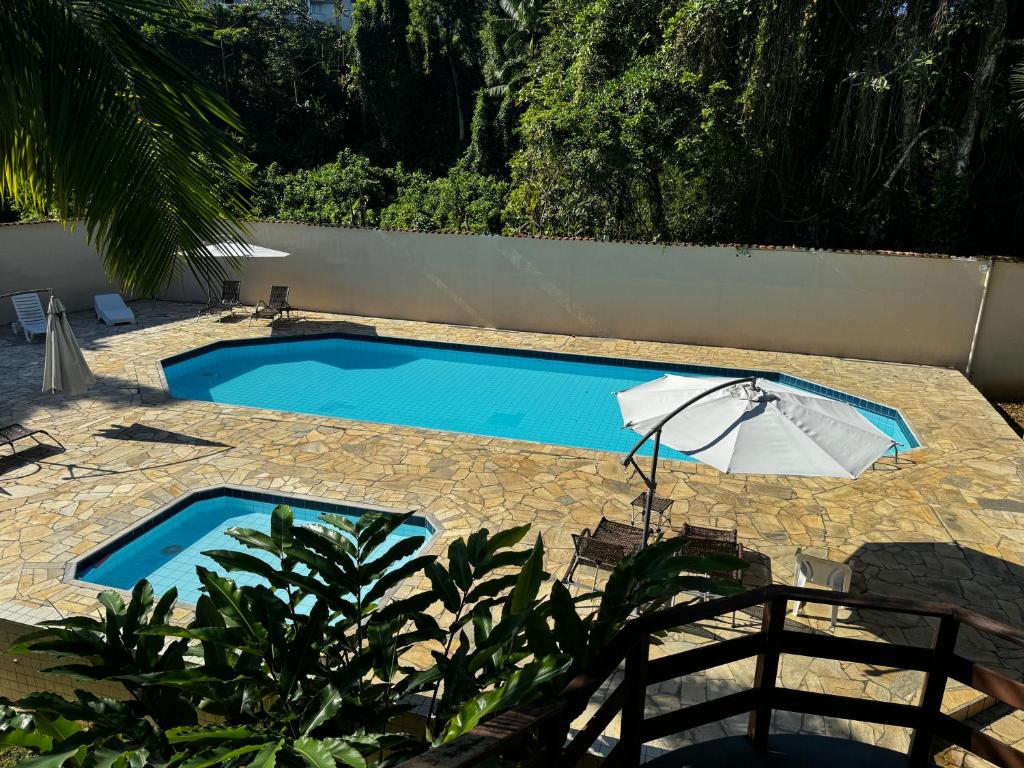 a blue swimming pool with an umbrella and an umbrella at LINDO APTO ITAGUA (UBATUBA) in Ubatuba