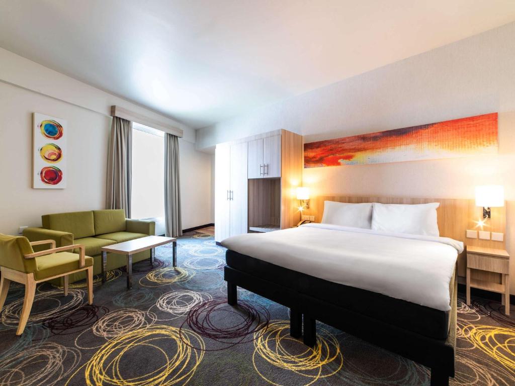 una camera d'albergo con letto e divano di Ibis Styles Dragon Mart Dubai a Dubai