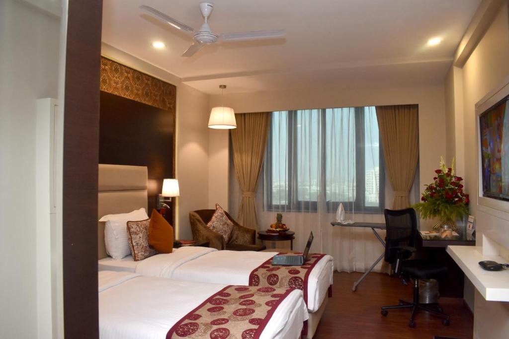 a hotel room with two beds and a desk at Lords Plaza Surat in Surat