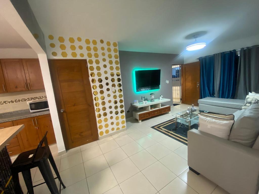 ein Wohnzimmer mit einem Sofa und einem TV in der Unterkunft Residencial Maite Vl in Santiago de los Caballeros