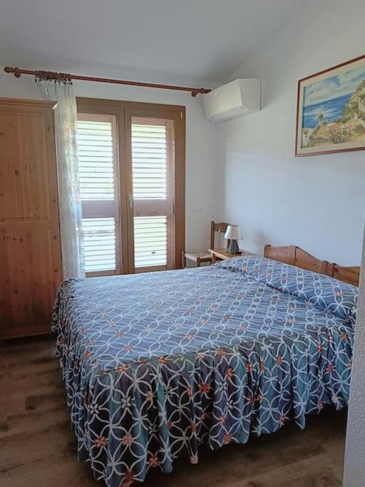 a bedroom with a bed with a blue blanket on it at Appartamento Luisa E in Villasimius