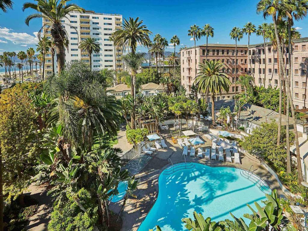 - une vue sur la piscine bordée de palmiers et de bâtiments dans l'établissement Fairmont Miramar Hotel & Bungalows, à Los Angeles