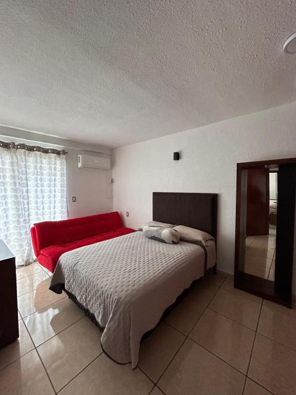 "Condominio Américas" في بوكاي ديل ريو: غرفة نوم بسرير كبير واريكة حمراء
