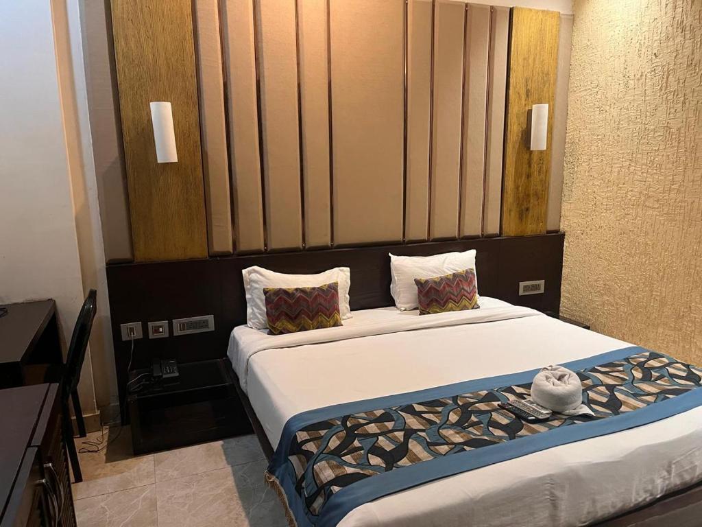 ein Schlafzimmer mit einem großen Bett mit weißer Bettwäsche und Kissen in der Unterkunft HOTEL JODHA THE GREAT in Agra