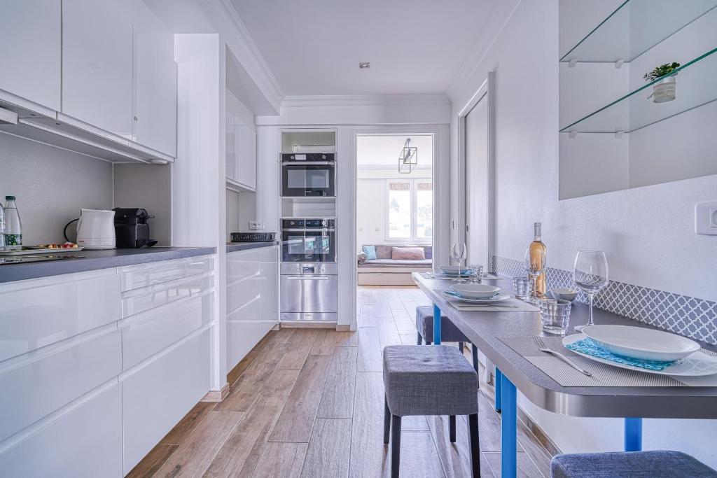 une cuisine avec des armoires blanches et une table avec des chaises dans l'établissement Le Marignan, à Cannes