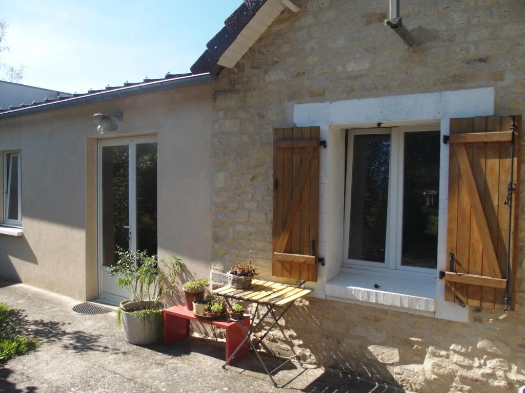 une maison en pierre avec des portes en bois et une table dans l'établissement Maison mes délices, à Caen