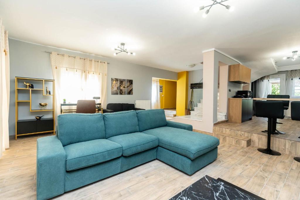 a living room with a blue couch and a kitchen at Heated Pool Villa in Thessaloniki - Urban Oasis in Thessaloniki
