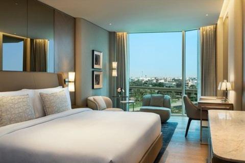ein Hotelzimmer mit einem Bett und einem großen Fenster in der Unterkunft Rosewood Suites Near IGI Airport in Neu-Delhi