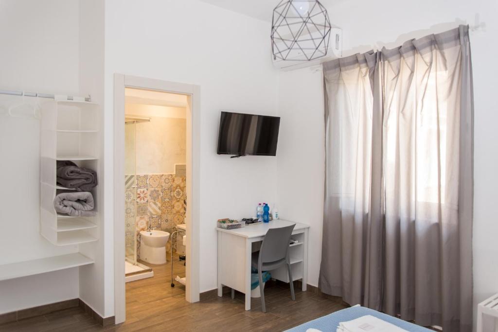 Habitación blanca con escritorio y espejo. en La Casa di Ninì en Agrigento