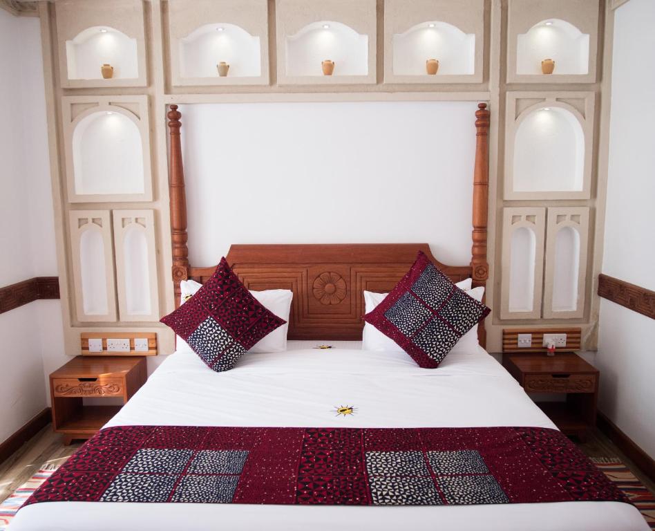 een slaapkamer met een groot bed met rode en blauwe kussens bij Small World Country Club in Athi River