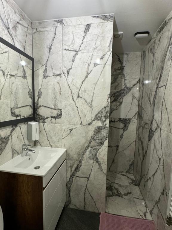 a bathroom with a sink and a marble wall at Bellas apartmani in Novi Sad