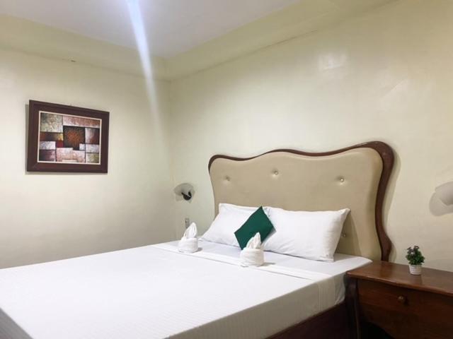 a bedroom with a large white bed with a wooden headboard at Palawan Rose Garden 1 in Puerto Princesa City