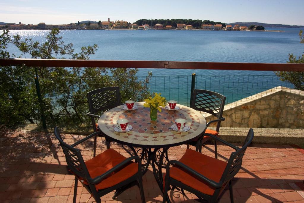 una mesa y sillas en un balcón con vistas al agua en Pansion Zlatna ribica, en Brodarica