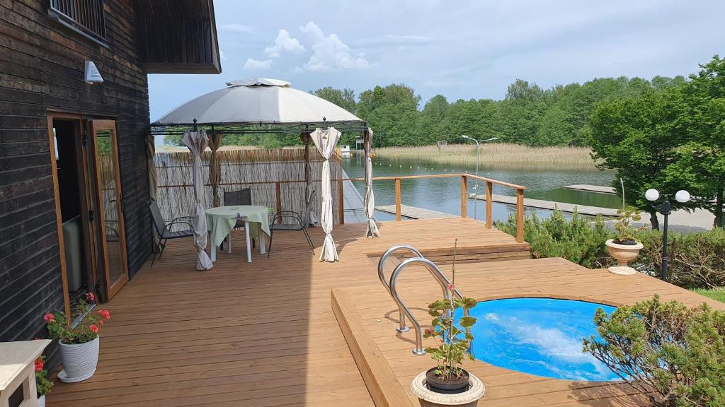 een houten terras met een prieel en een zwembad bij Prie Galvės in Trakai