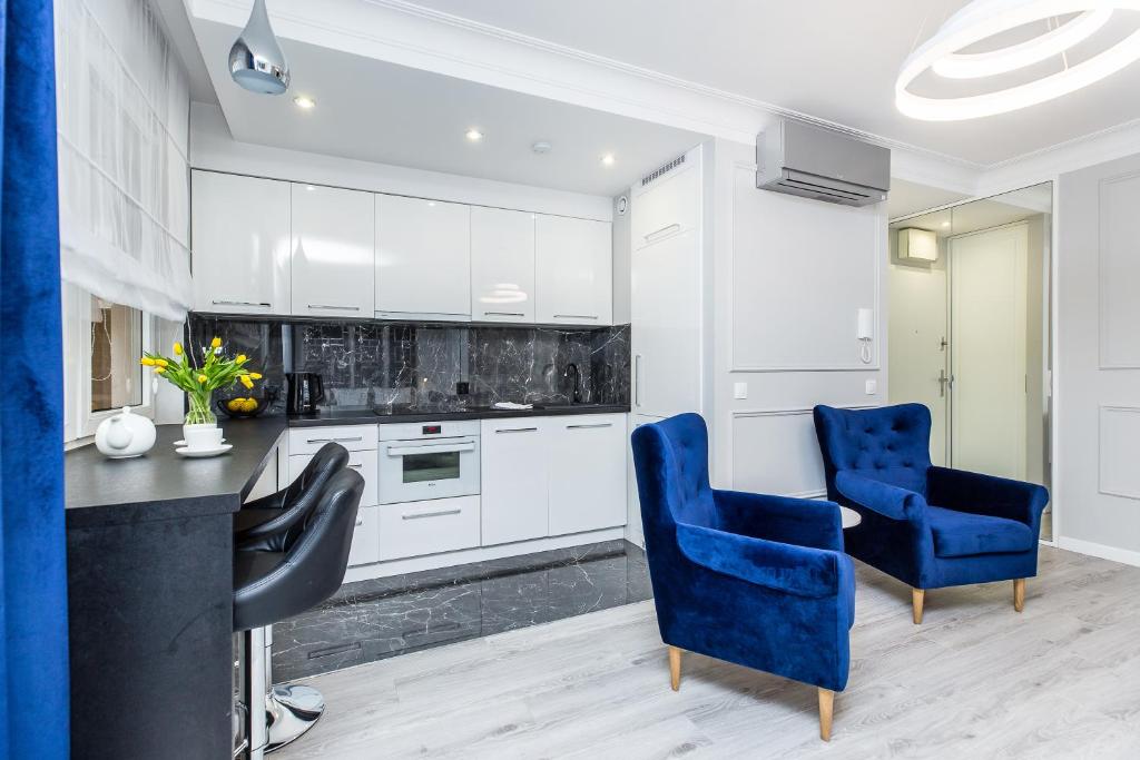 a kitchen with white cabinets and blue chairs at Premium Glamour Apartment by Krakow Home in Kraków