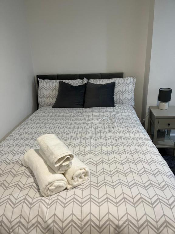 a bed with towels and pillows on top of it at Stylish and Spacious Wi-Fi Smart TV Tea and coffee in Kettering