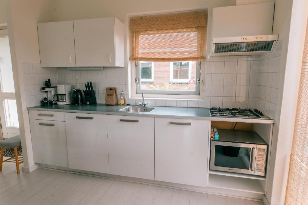 a white kitchen with a sink and a microwave at Rekerlanden 275 in Warmenhuizen