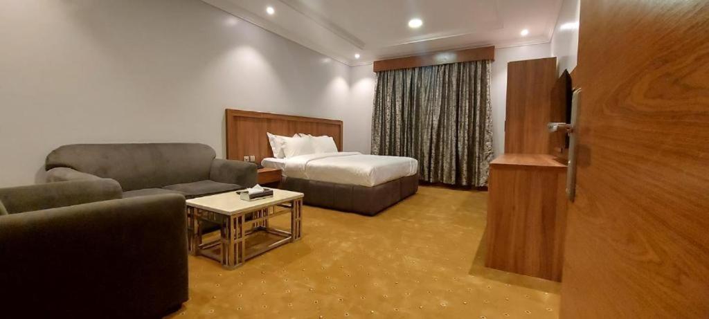 une chambre d'hôtel avec un lit et un canapé dans l'établissement الماسم للأجنحة المخدومة- الملك فهد, à Riyad