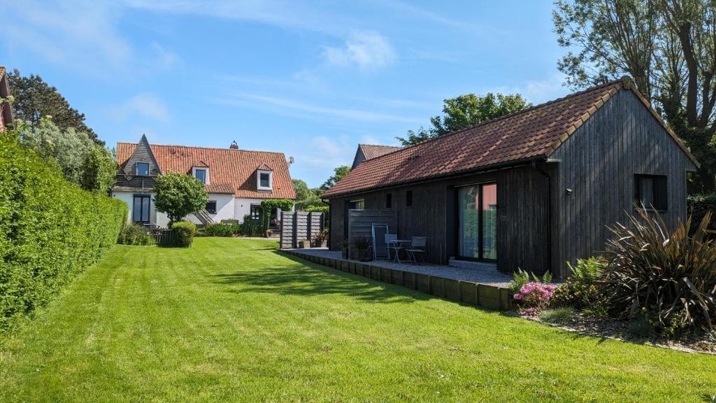 La Rogeraie Cap gris nez في أودينجين: منزل أسود صغير مع ساحة عشب