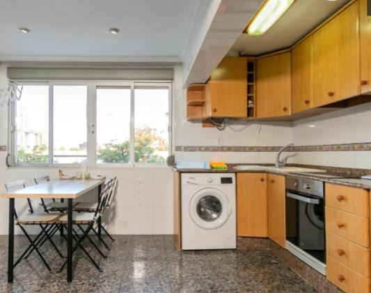 a kitchen with a table and a washing machine at Habitaciones y Suite. UPV, UV y Playa in Valencia