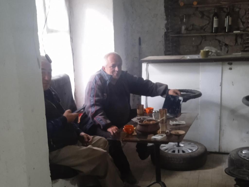 two men sitting around a table in a room at avtostop.bicykle.tent in Meghri