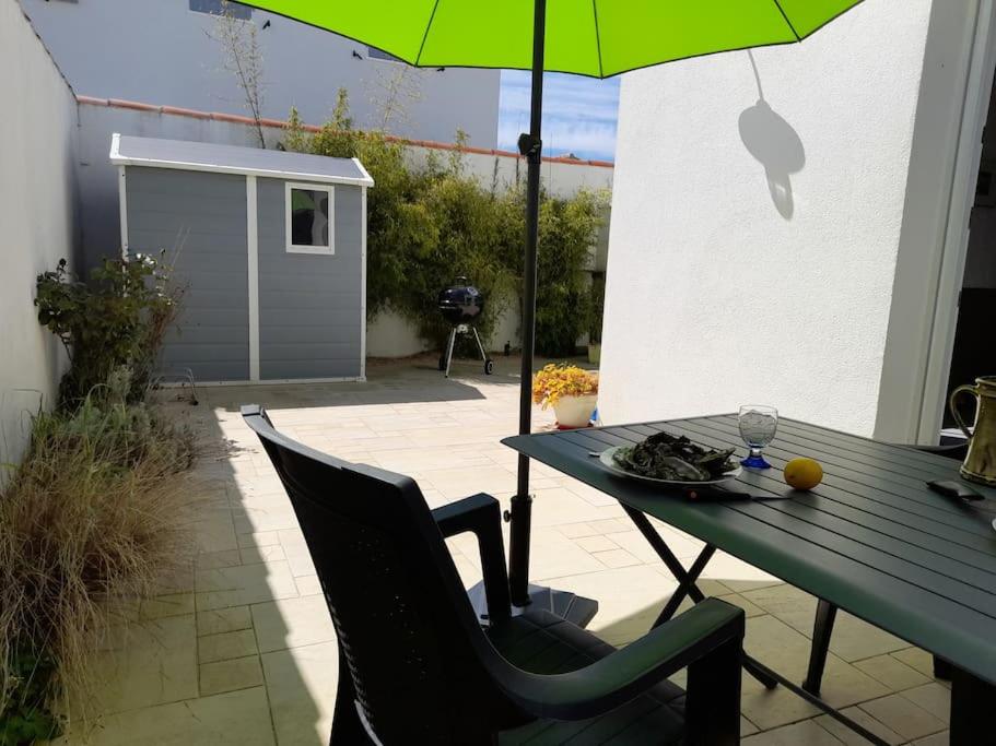 - une table avec un parasol vert sur la terrasse dans l'établissement La Flotte Lumineuse maison de charme très calme, à La Flotte