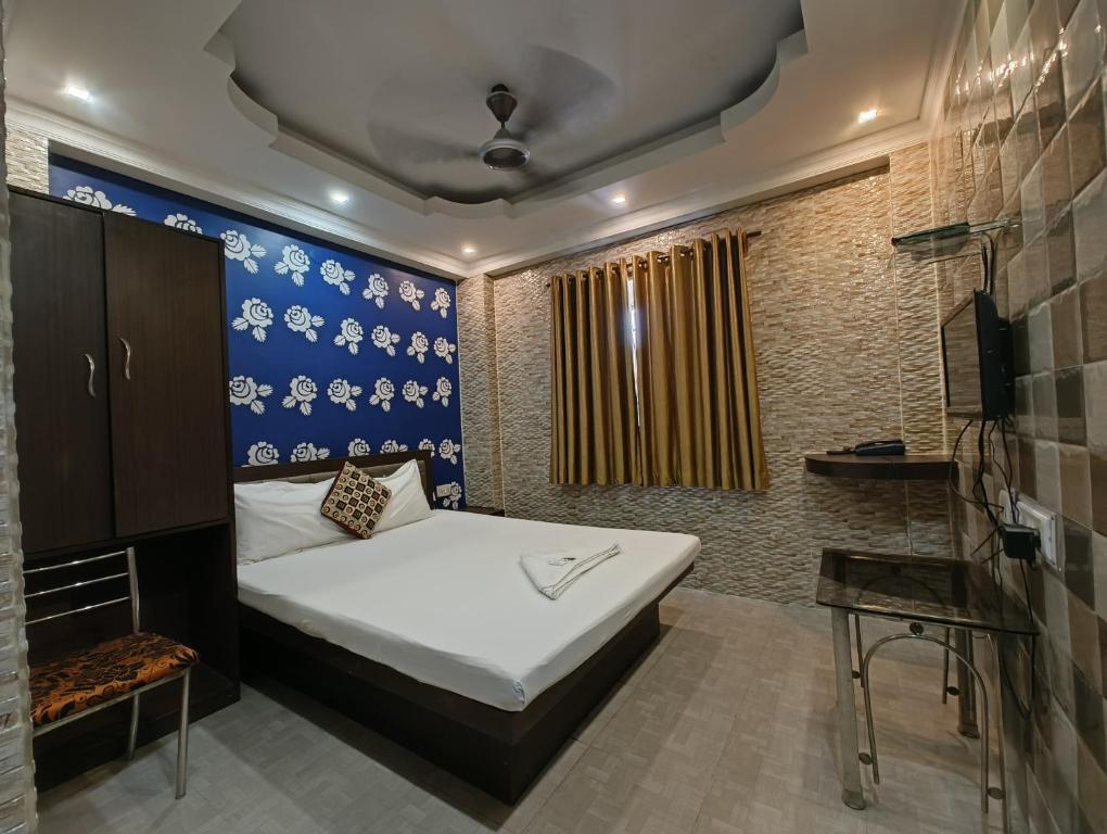 Golden Heaven Hotel في كولْكاتا: غرفة نوم بسرير وجدار ازرق