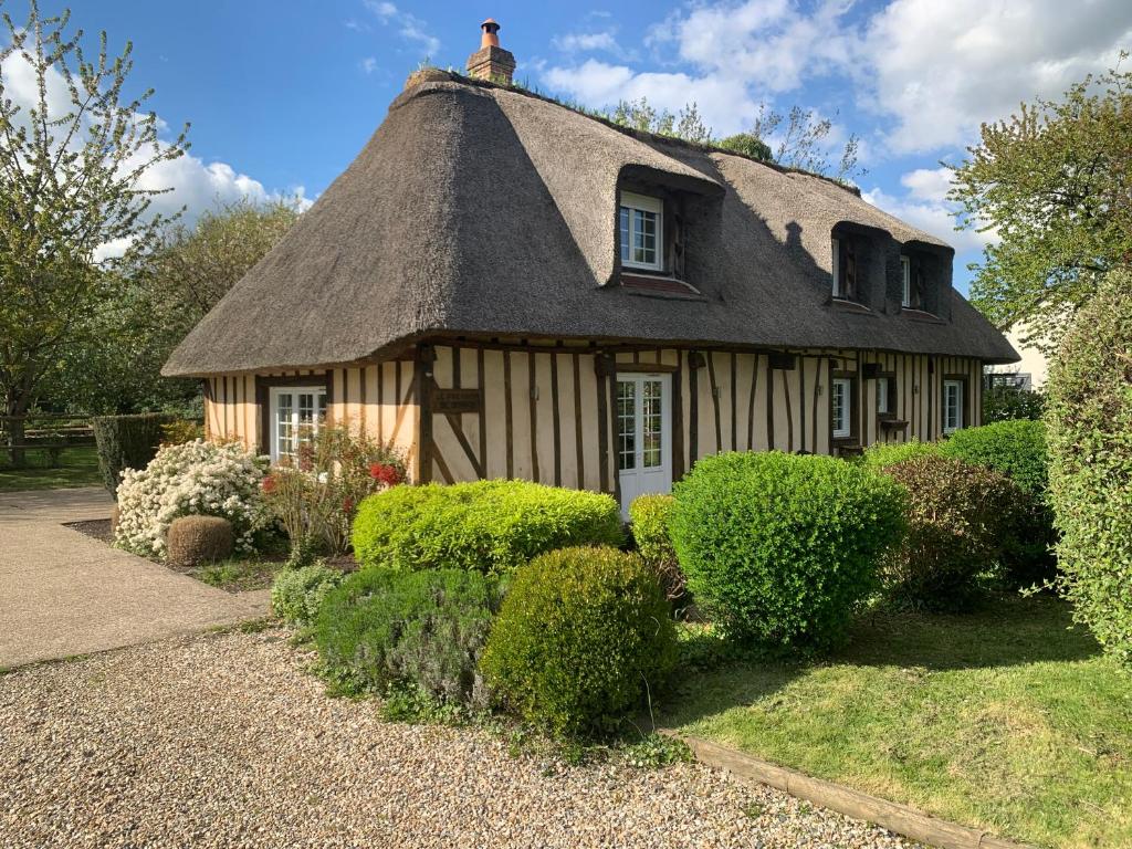 une maison ancienne avec un toit de chaume et quelques buissons dans l'établissement Le Pressoir de Bigard, à Campigny