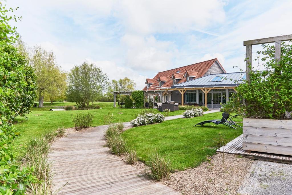 a house with a wooden walkway in front of a yard at Domaine Les Saules Hôtel Restaurant Spa in Favières