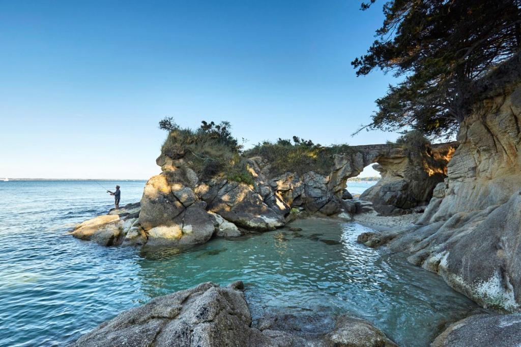une personne debout dans l'eau sur une plage rocheuse dans l'établissement Villa Ty Clipper plage à pied, à Fouesnant