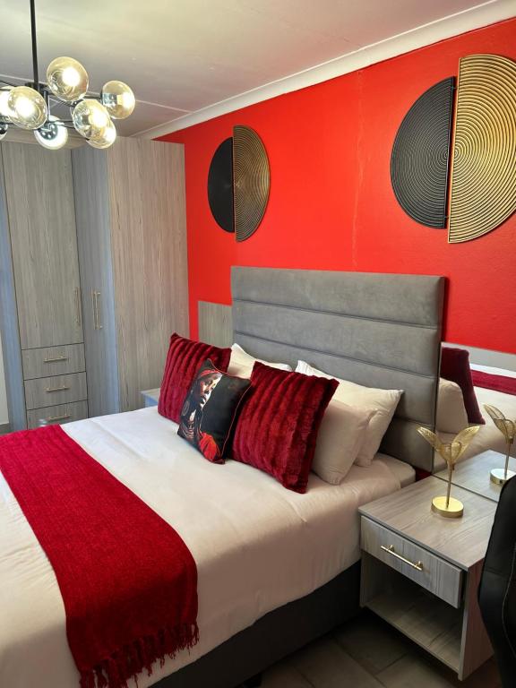 a bedroom with a bed with a red wall at SiBella guest house in Bloemfontein