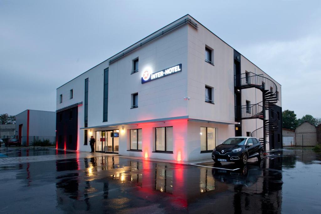 a building with a car parked in front of it at The Originals City, Hôtel Marne-la-Vallée Est, Meaux in Meaux