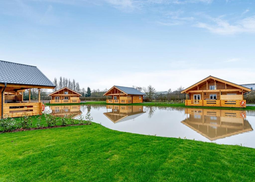 een groep houten huizen aan een meer bij Holly Tree Lodges in York