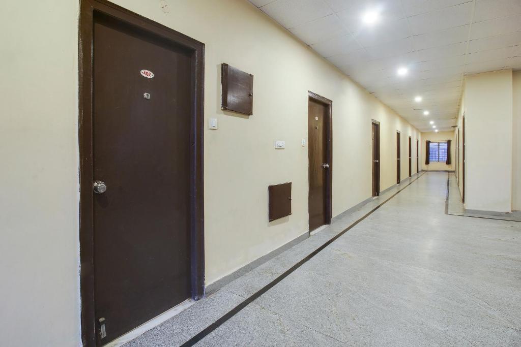 an empty hallway with black doors and a long corridor at Super OYO Anuguna Tulasi Grand Near JNTU University Hyderabad in Kukatpalli